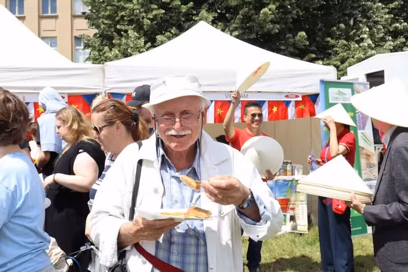 Visitors enjoy fried spring rolls at the Vietnamese Embassy’s food stall. (Photo: VNA)