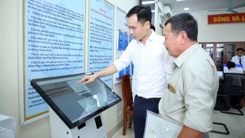 Guiding residents through administrative procedures at the Public Administration Service Point in Phuc Thinh Commune, Ha Noi. (Photo: NHAT NAM)