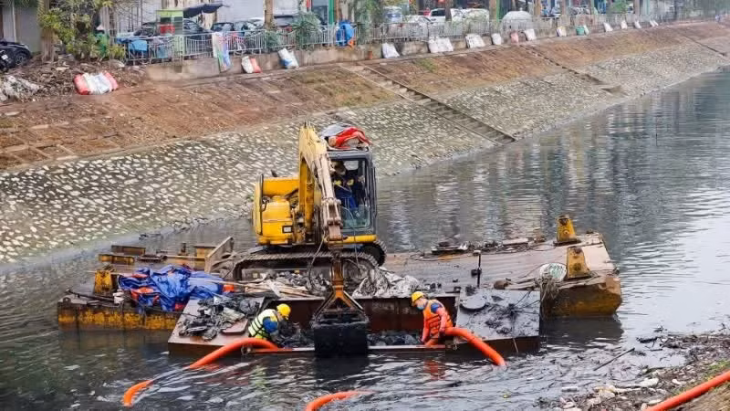 Workers from Ha Noi Drainage Company dredge sludge from the To Lich River.
