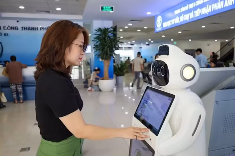 People use an AI-powered robot to receive guidance and advice on administrative procedures at Branch No. 1 of the Ha Noi Public Administrative Service Centre. Photo: LE HAI