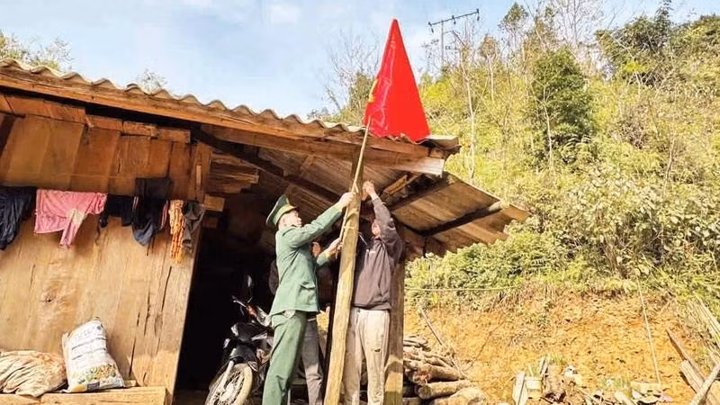 An officer of Xuan Truong Border Guard Station hoists the national flag together with a resident of a border hamlet.
