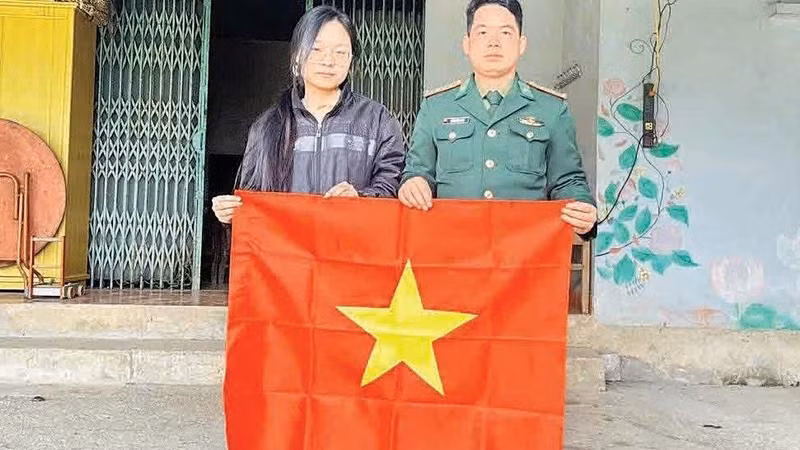 An officer of Xuan Truong Border Guard Station presents a national flag to a resident of a border hamlet.