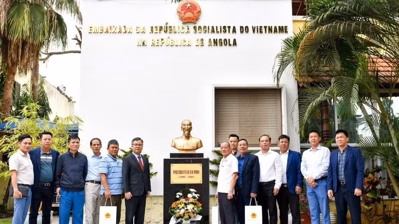 Vietnamese Ambassador to Angola Duong Chinh Chuc and Vietnamese veterans pose for a commemorative photo beside the President Ho Chi Minh Monument on the Embassy's premises. (Photo: Embassy of Viet Nam in Angola)