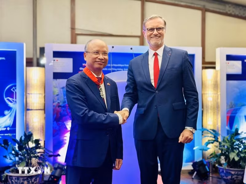 Authorised by the French President, French Ambassador to Viet Nam Olivier Brochet gives the noble order to Former Vietnamese Ambassador to France Dinh Toan Thang at a ceremony in Ha Noi on August 26 (Photo: VNA)