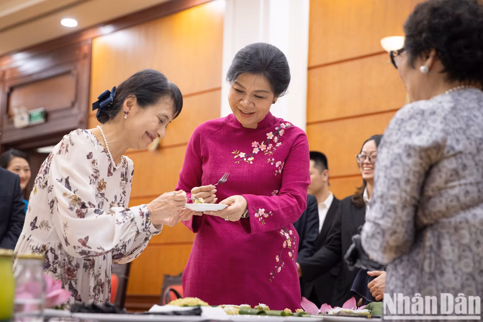 The two ladies taste the banh com they made.