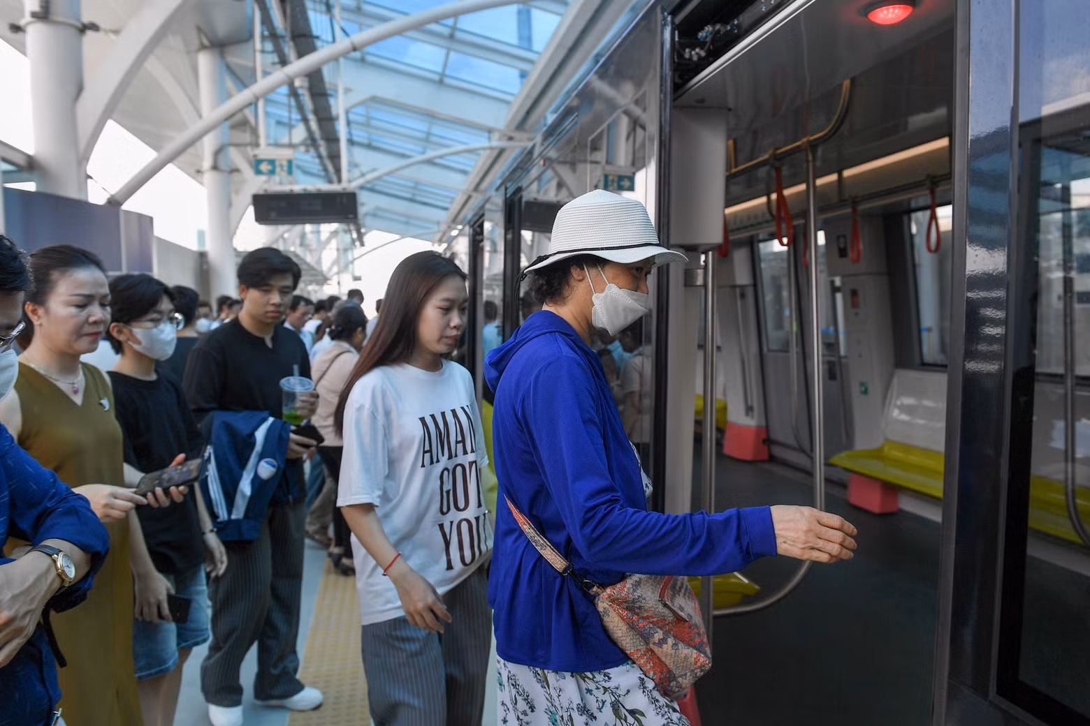People queue in line to experience the metro line on its first day of operation.