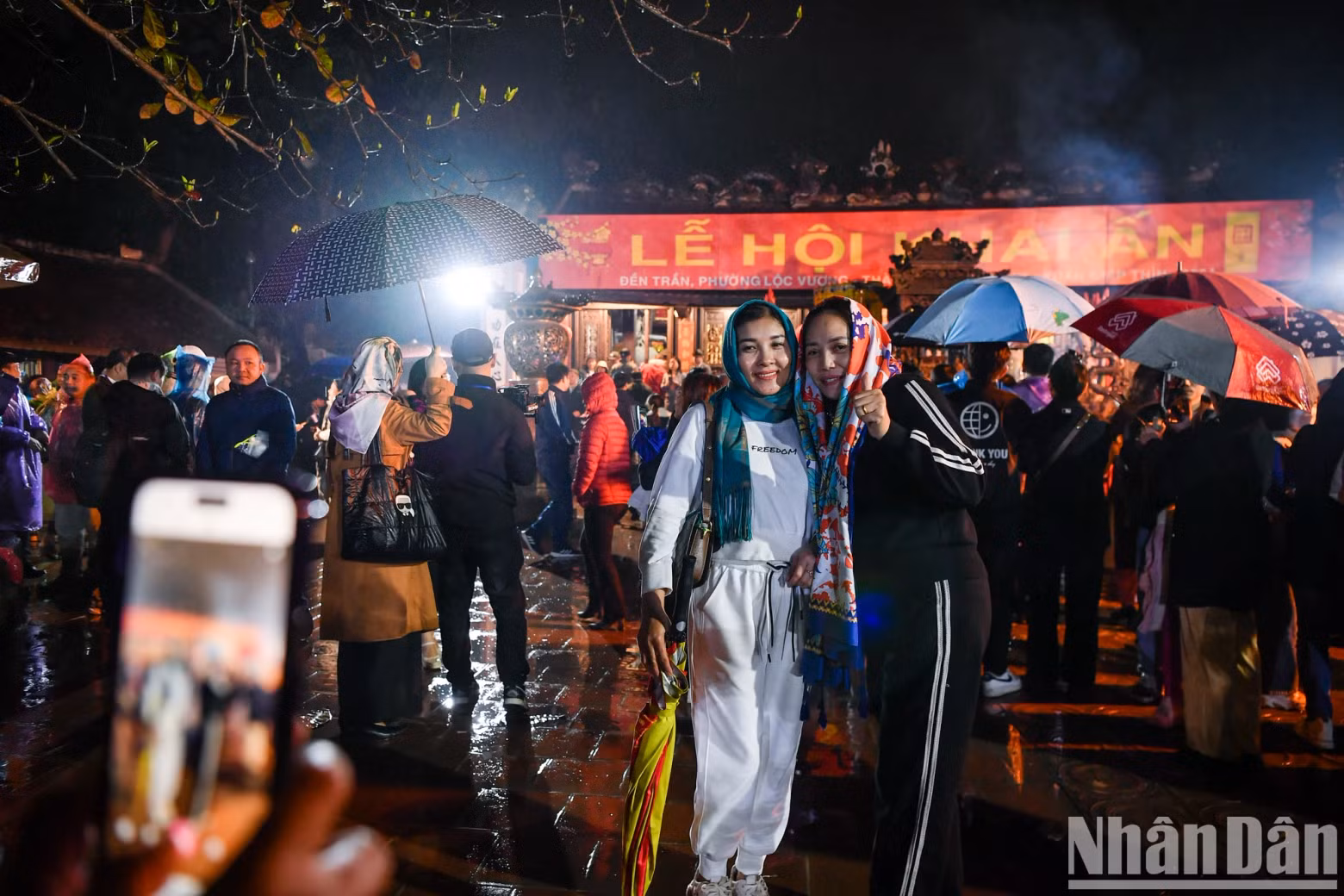 Two female tourists take a photo of this year's opening ceremony at Tran Temple.