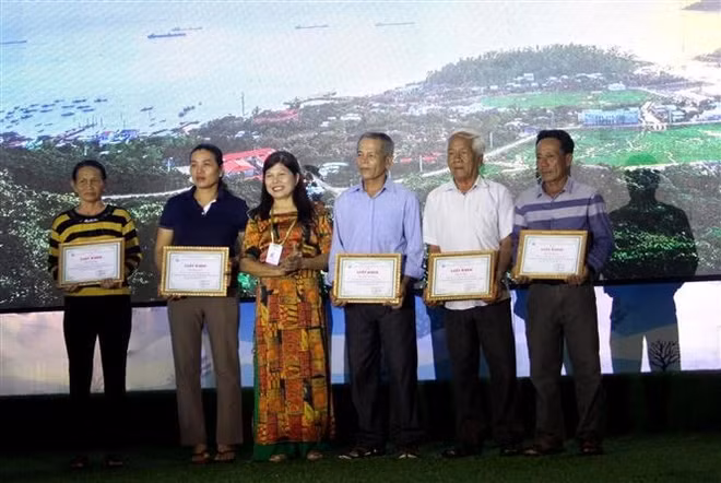 The persons contributing to UNESCO's recognition of Cu Lao Cham - Hoi An as a world biosphere reserve receive certificates of merit from the administration of Tan Hiep island commune in Hoi An city, Quang Nam province, at the ceremony on May 23. (Photo: VNA)