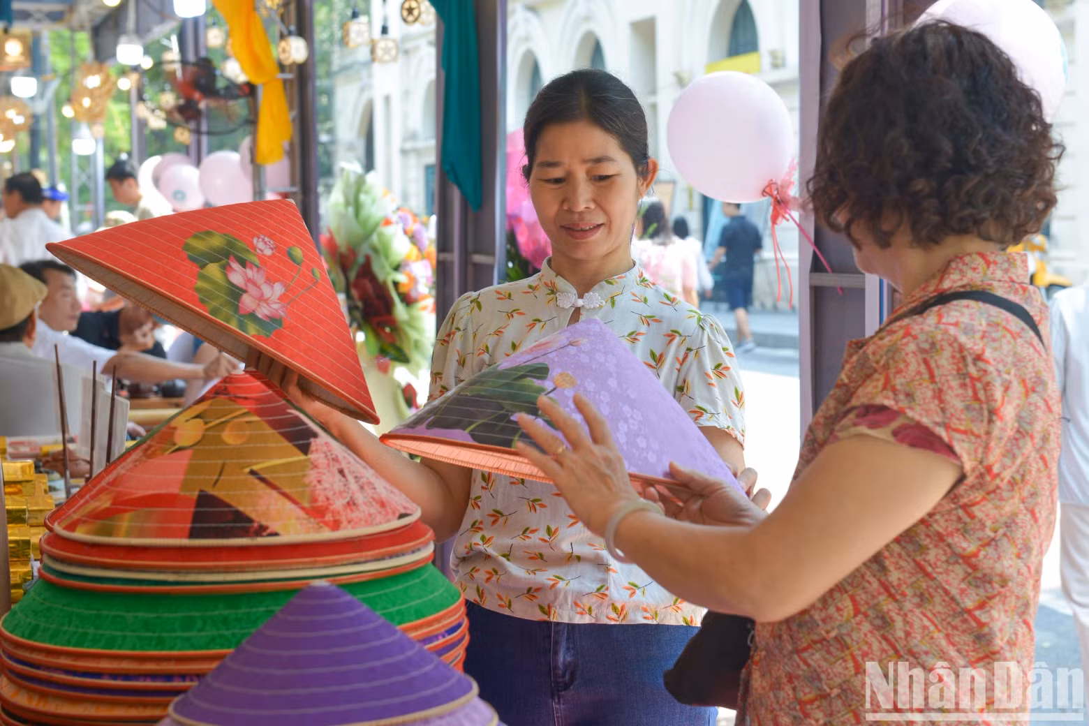 Many visitors enjoy the conical hats with eye-catching patterns at the booth of the Chuong conical hat village from Thanh Oai District, Hanoi.