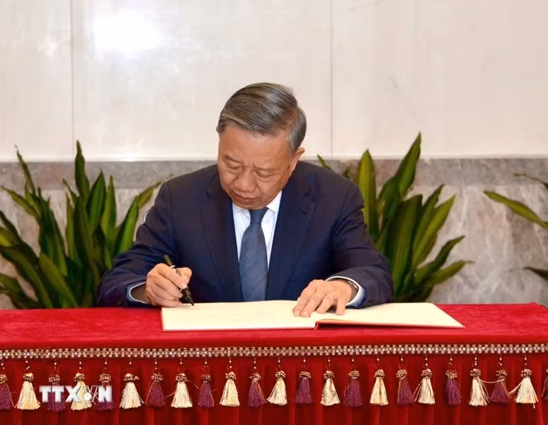 General Secretary and President To Lam writes in the guest book at the memorial house.