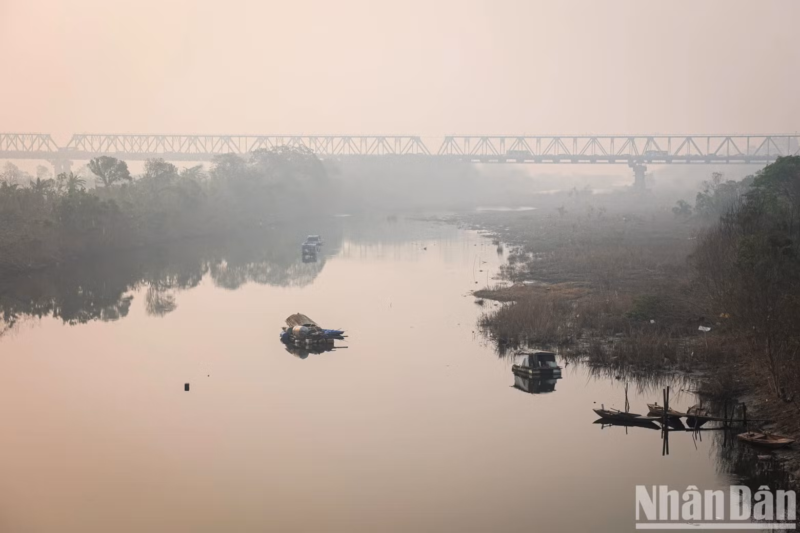 Looking towards Chuong Duong Bridge, we can see the tranquil scene of the bridge along with boats casting reflections on the Red River, creating a peaceful and poetic atmosphere.