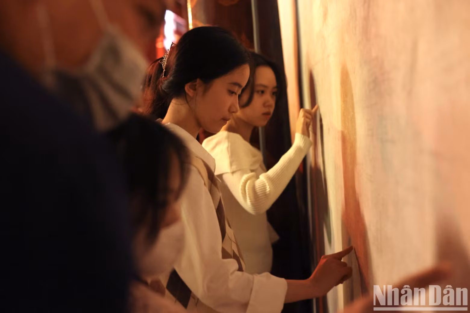 Young people are excitedly writing their wishes for a new successful year on the wall by hand.