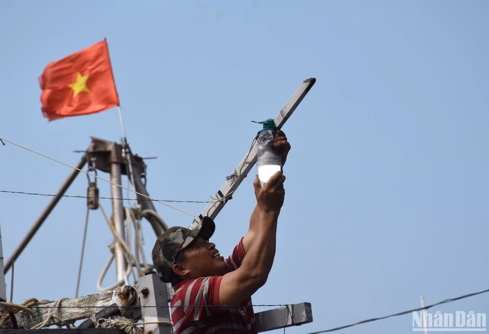 A fisherman is checking and reinstalling light bulbs on a fishing boat…