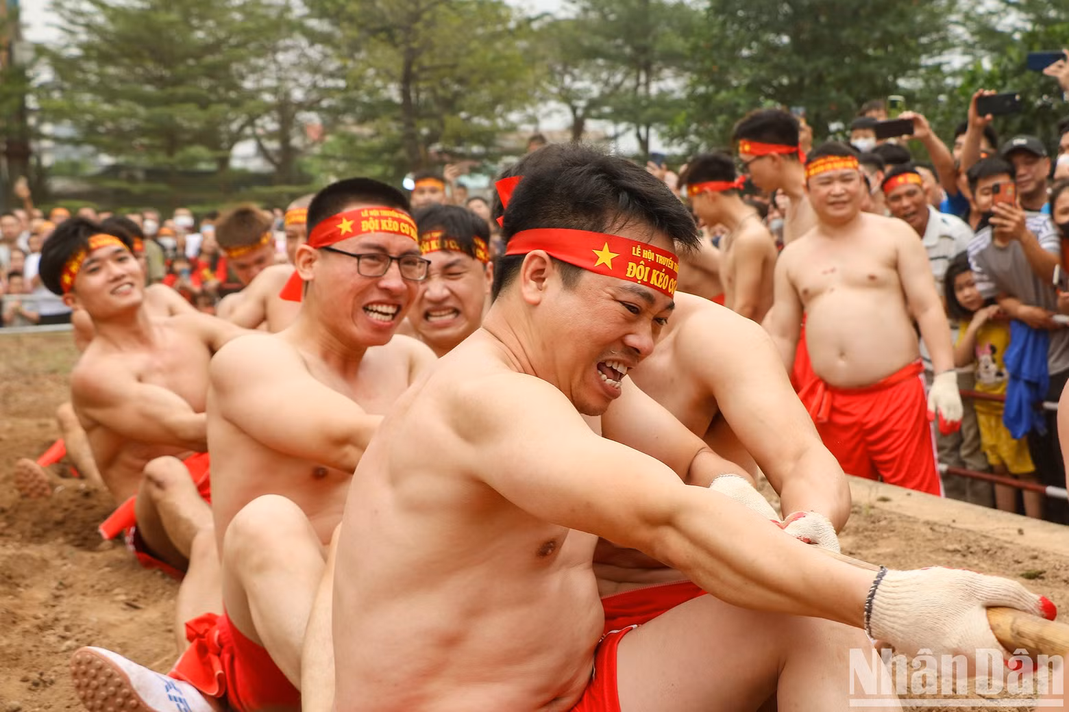 Each person uses their hands to hold the bamboo pole and step into a deep hole in the ground with their feet. Most of the participants are healthy and muscular young men.