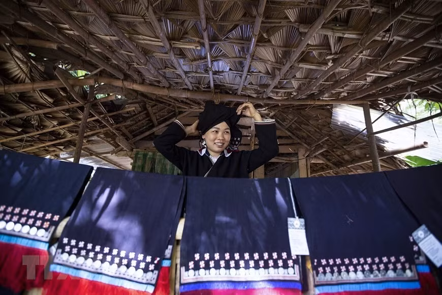 A Dao Tien girl stands behind brocade headscarves printed with beeswax patterns. (Photo: Trong Dat/VNA)