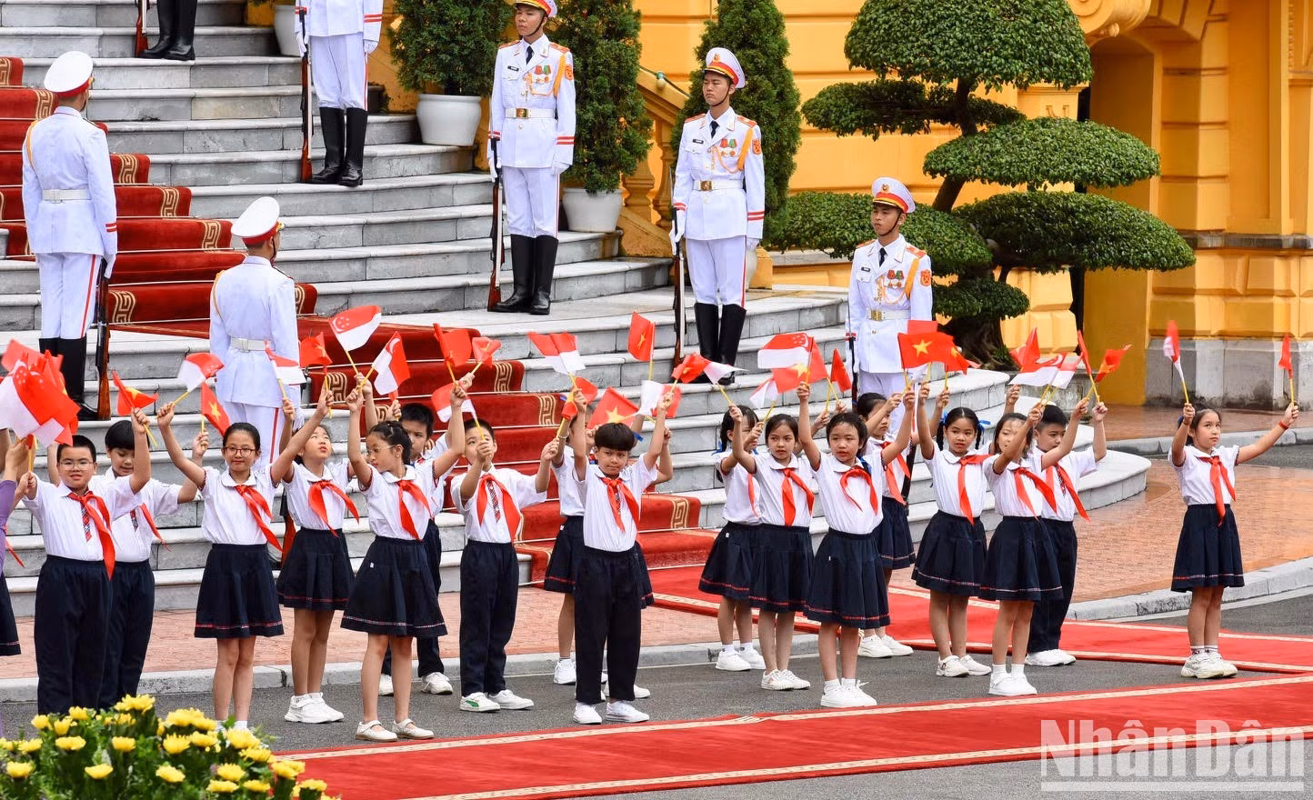Children waves the national flags of Vietnam and Singapore to welcome the two PMs.
