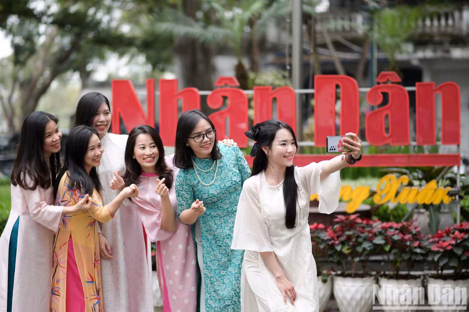 Female reports and employees together capture beautiful moments in the courtyard of Nhan Dan Newspaper.