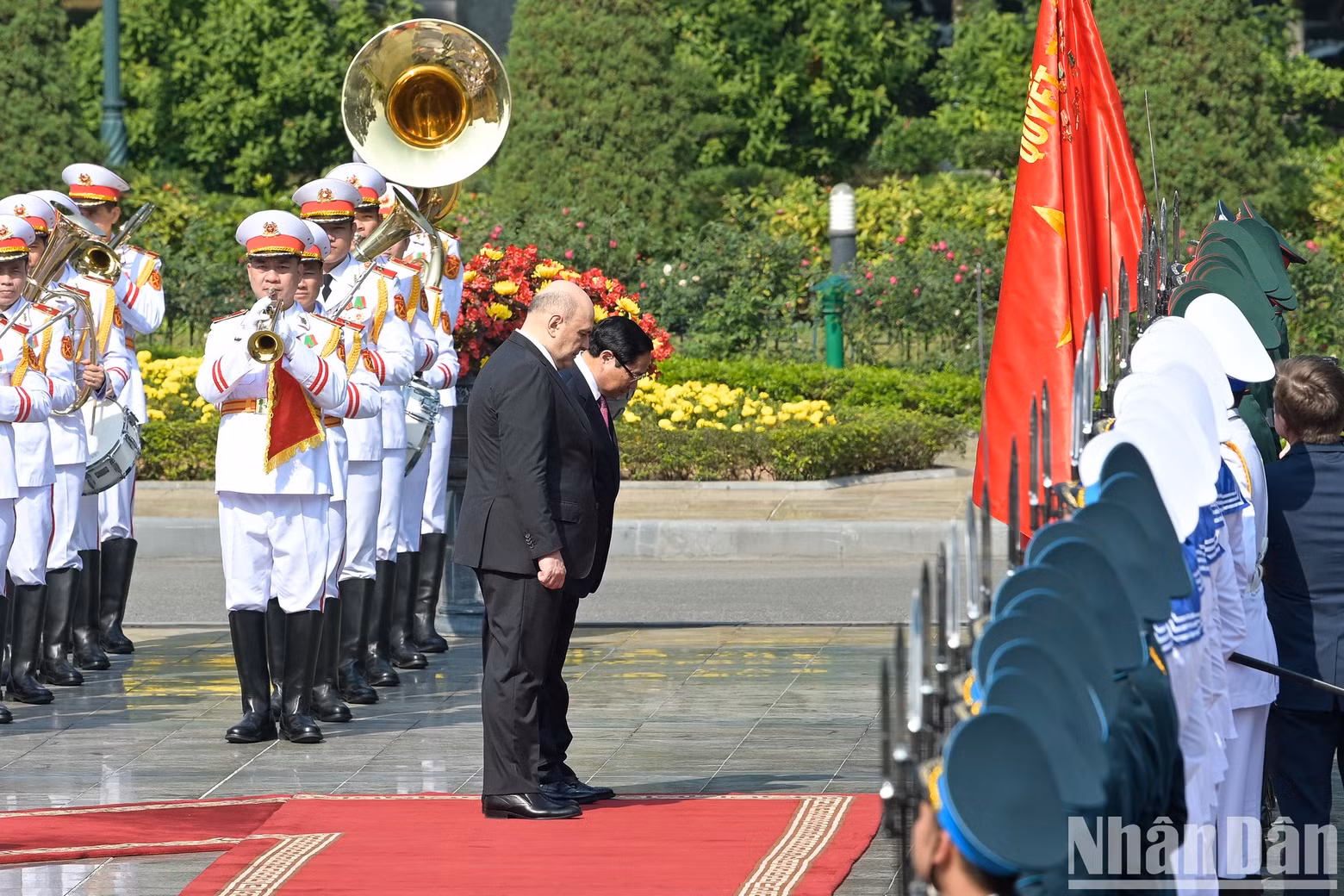 The two Prime Ministers bow to Vietnam’s military victory flag.