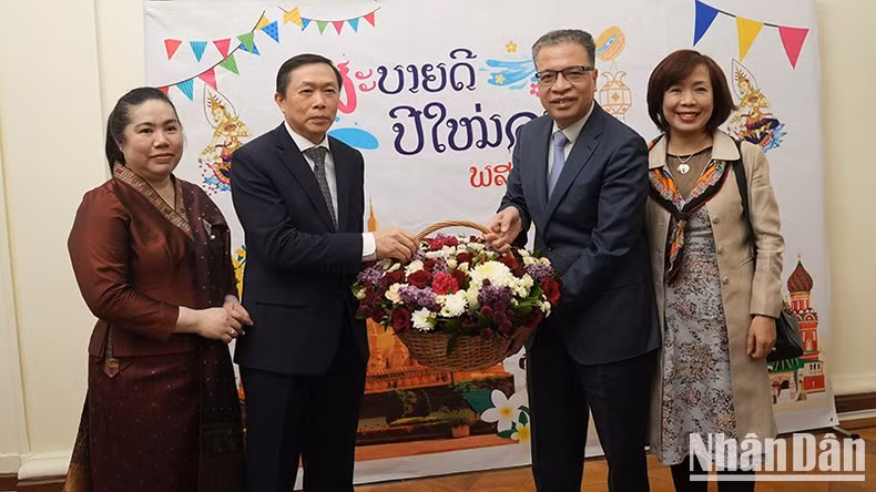 Ambassador Dang Minh Khoi presents flowers and extends his best wishes to Ambassador Siphandone Oybuabuddy.
