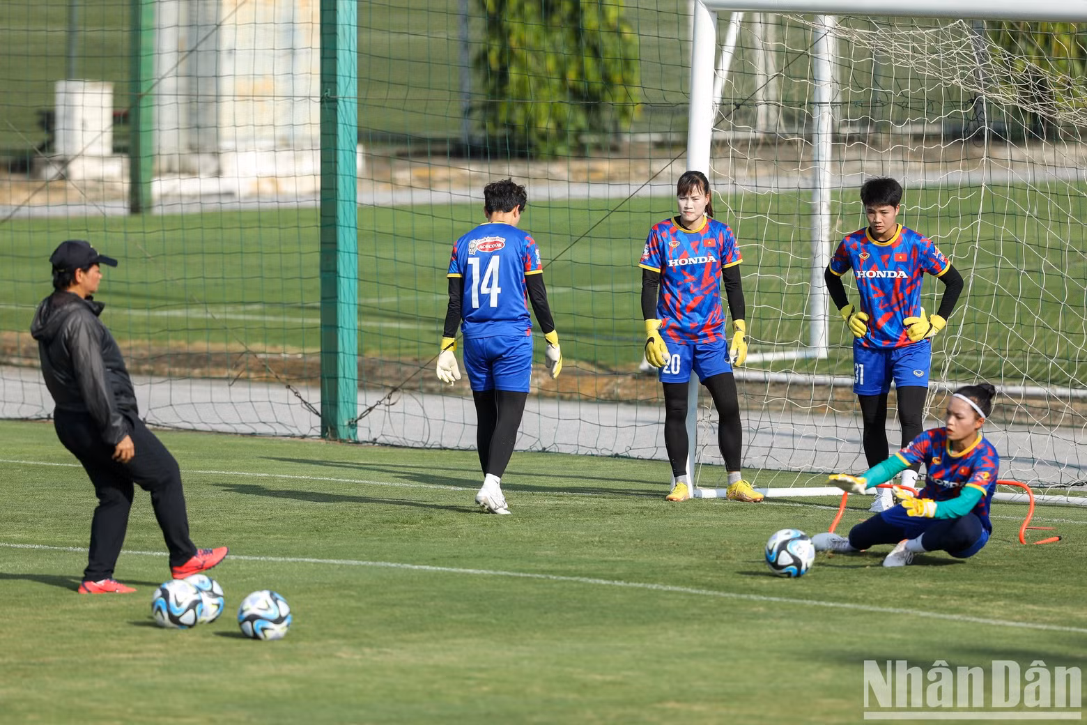 Goalkeepers do sets of exercises under the instruction of an assistant coach.