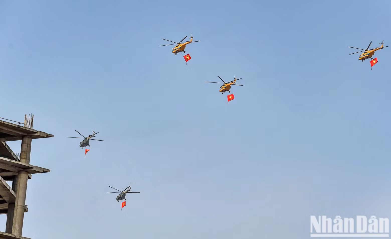 Mi-8 and Mi-17 helicopters flying with the Party and National flags toward the grandstand.