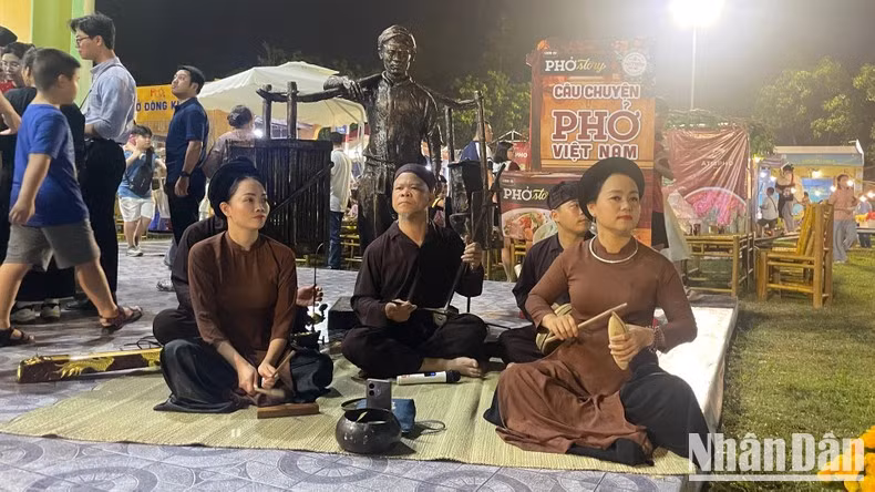 Xam (Vietnamese folk singing) performance beside a traditional pho vendor statue.