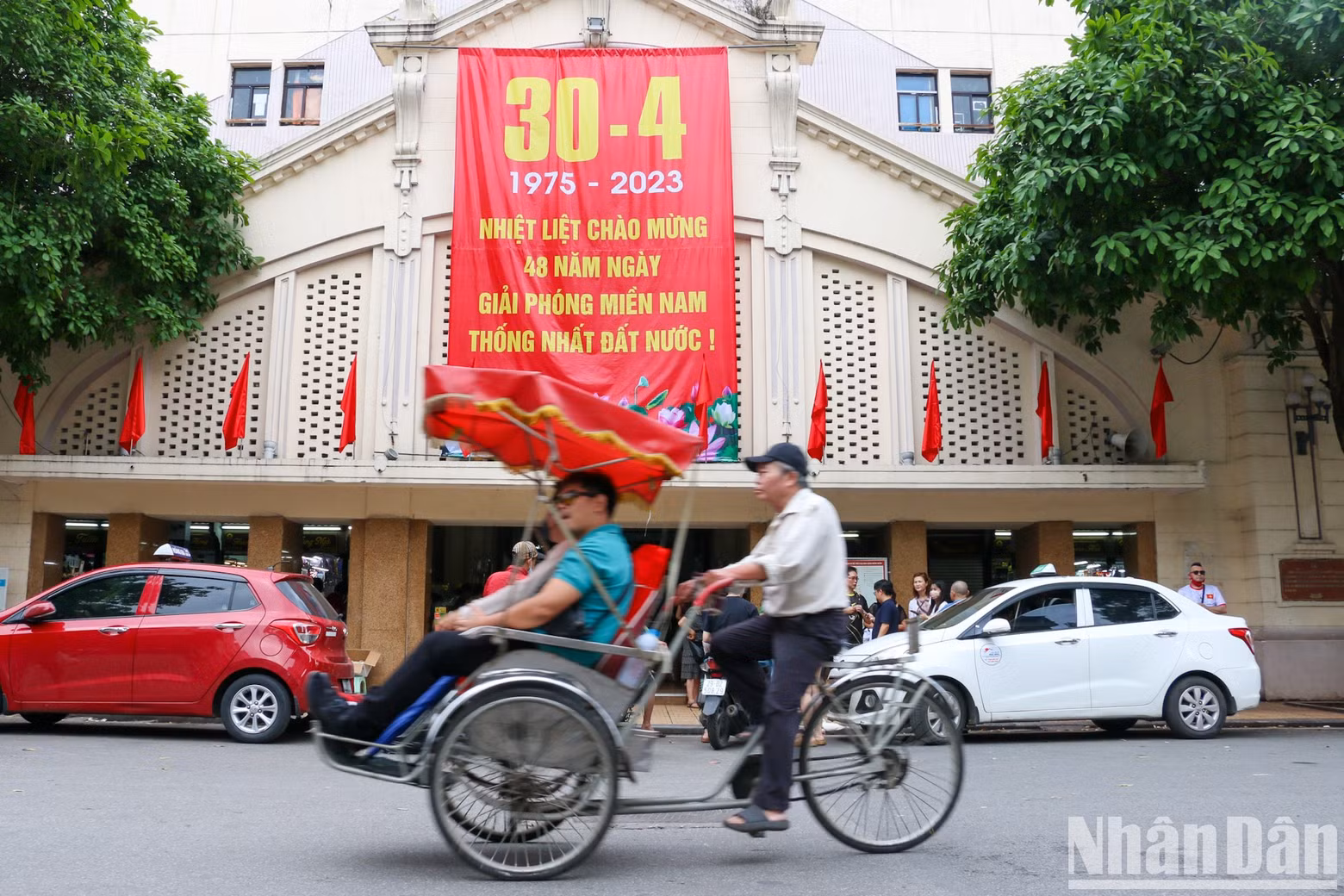 A large-format poster celebrating National Reunification Day is hung at Dong Xuan Market.