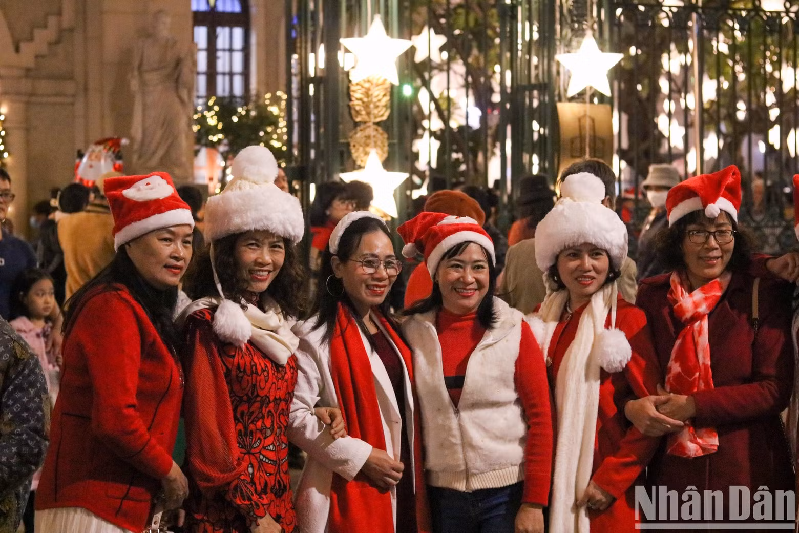 A group of women wearing red Santa Claus hats poses for a photo outside the entrance of Ham Long Church in Hoan Kiem District, Hanoi. (Photo: Nhat Quang)