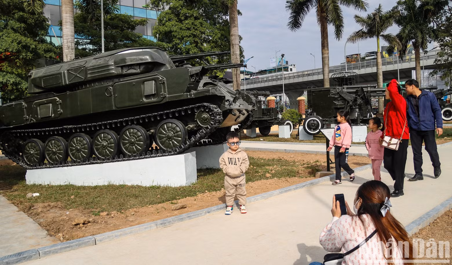 A boy standing in front of a tank on display at the museum.