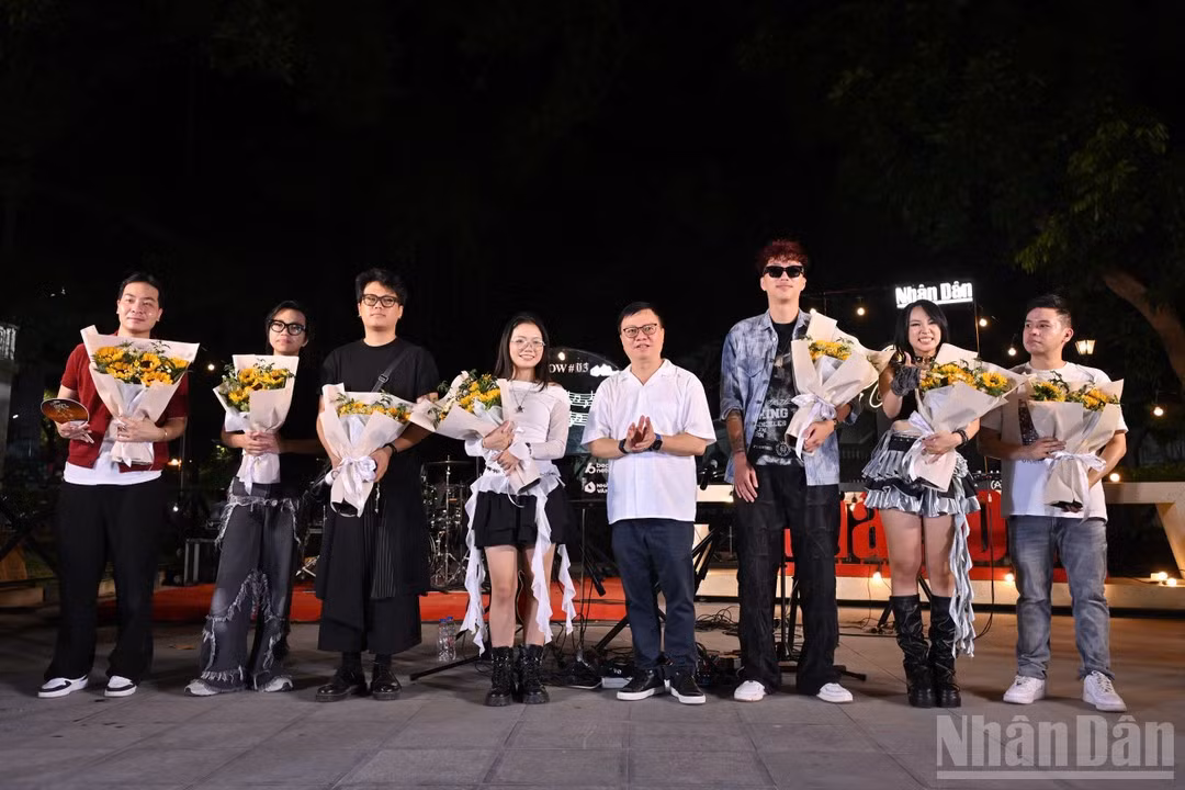 Nhan Dan Editor-in-Chief Le Quoc Minh presents flowers to the artists and bands performing in the programme.