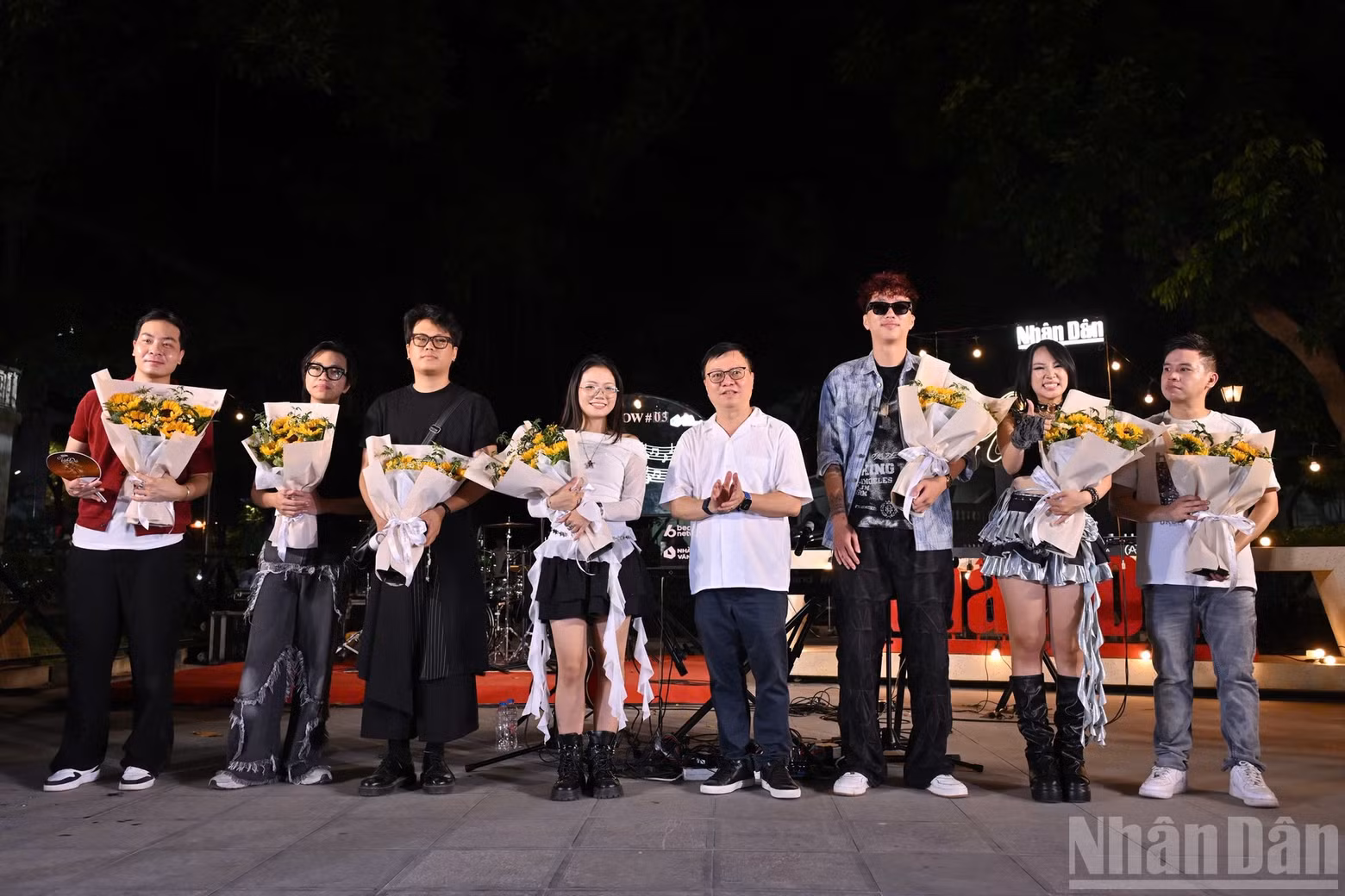 Nhan Dan Editor-in-Chief Le Quoc Minh presents flowers to the artists and bands performing in the programme.