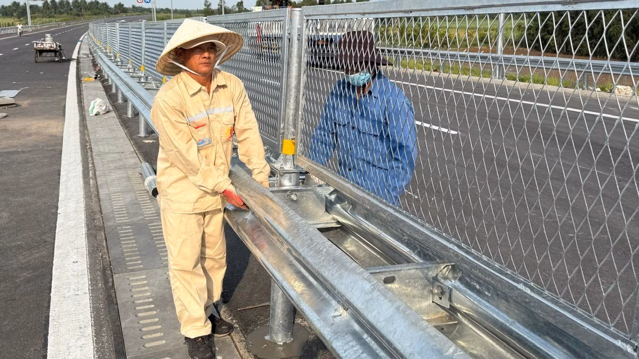 Workers conduct final checks and install safety fencing along the expressway ahead of its opening. (Photo: QUY HIEN)