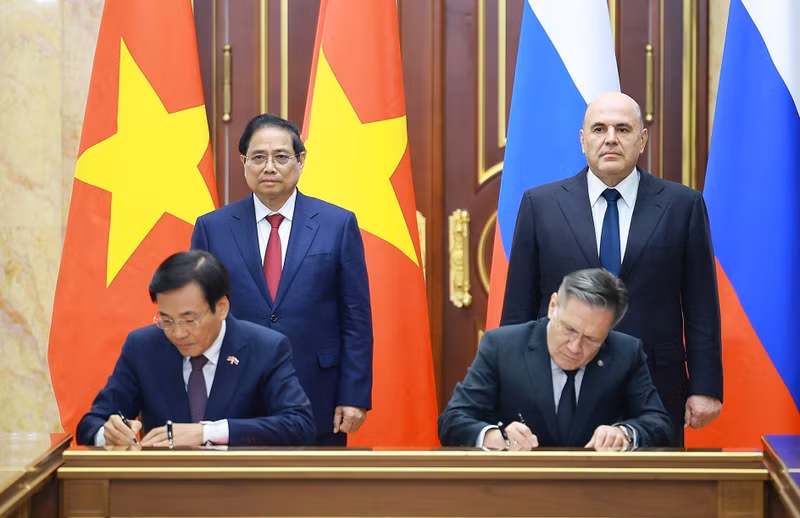 Vietnamese PM Pham Minh Chinh (standing, left) and his Russian counterpart Mikhail Mishustin (standing, right) witness the signing of the agreement between the two governments on cooperation in building a nuclear power plant on the territory of Viet Nam. (Photo: VNA)
