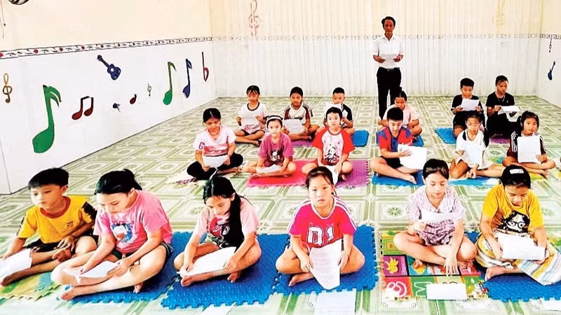 Meritorious Artisan Ngo Tri Minh teaches Vi and Giam folk songs to children.