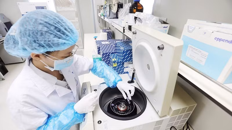 A technician places a DNA extraction sample in a centrifuge. (Photo: MINH LE)