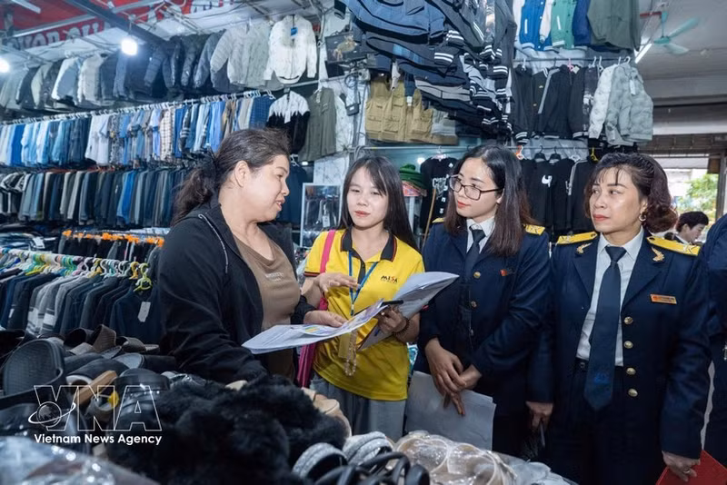 Tax officers give guidance to a small trader at a market. Under Decree No. 141/2026/ND-CP, the household businesses with annual revenue of 1 billion VND or less will not have to pay personal income tax and value-added tax. (Photo: VNA)