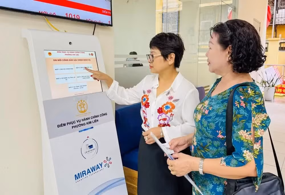 Civil servants at the Kim Lien Ward public administrative service centre assist residents in obtaining queue numbers for administrative procedures. Photo: KHANH HUY