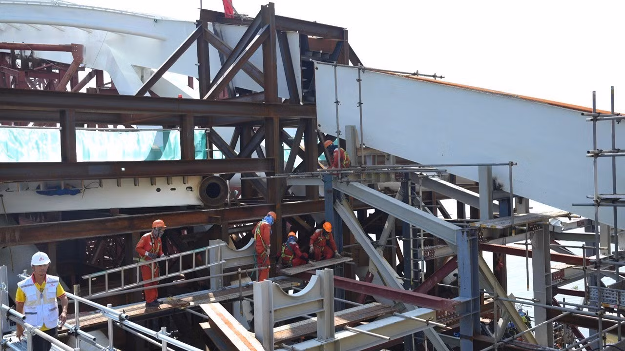 Workers and engineers labour to prepare the approach for installing the pedestrian bridge’s arched structure onto the two piers on opposite banks of the Sai Gon River. (Photo: THE ANH)