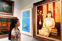 A visitor admires paintings at the exhibition.