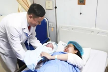 Associate Professor Dr Vu Van Du, Deputy Director of the National Hospital of Obstetrics and Gynaecology, congratulates the mother.