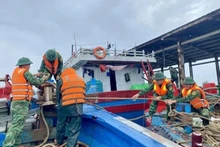 Border guards assist fishermen in reinforcing and securing their boats. (Photo: VNA)