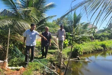 Nam Dau (middle) and local officials visit the site to resolve the conflict over land between two households.