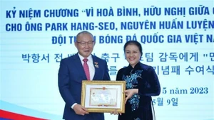 Ambassador Nguyen Phuong Nga (right) presents the insignia to coach Park Hang-seo. (Photo: VNA)