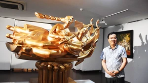 Painter and sculptor Dinh Gia Thang beside his sculpture “Roots of Happiness.”