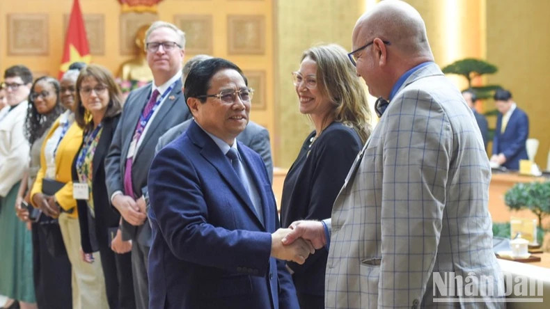 Prime Minister Pham Minh Chinh (L) receives representatives of 21 leading US universities, who are participating in the International Academic Partnership Programme (IAPP) in Vietnam. (Photo: NDO)