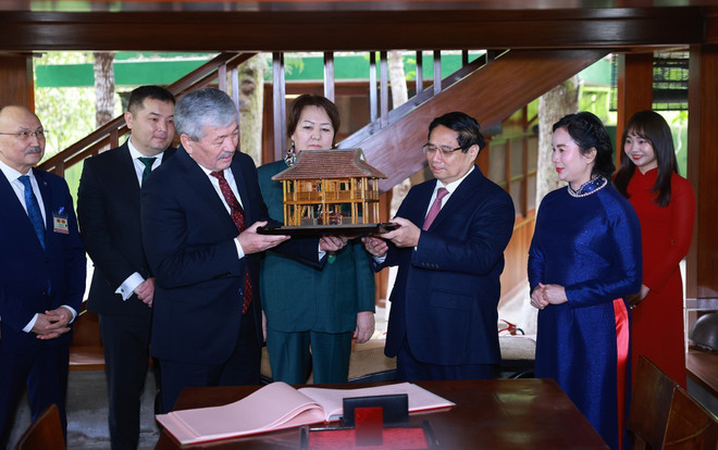 Prime Minister Pham Minh Chinh (R) presents a mock-up of President Ho Chi Minh's stilt house to Kyrgyzstan's Prime Minister Adylbek Kasymaliev (Photo: VNA)