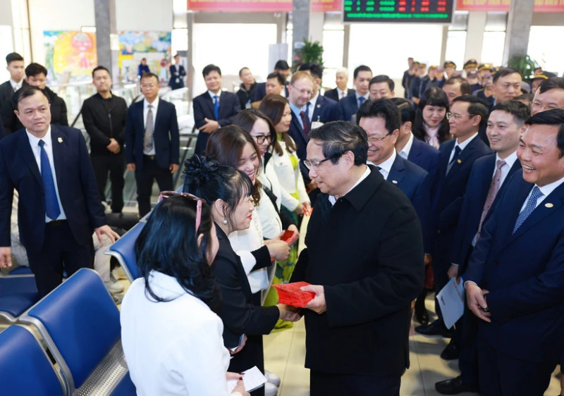 Prime Minister Pham Minh Chinh presents lucky money to passengers at the Hanoi Railway Station. (Photo: VNA)