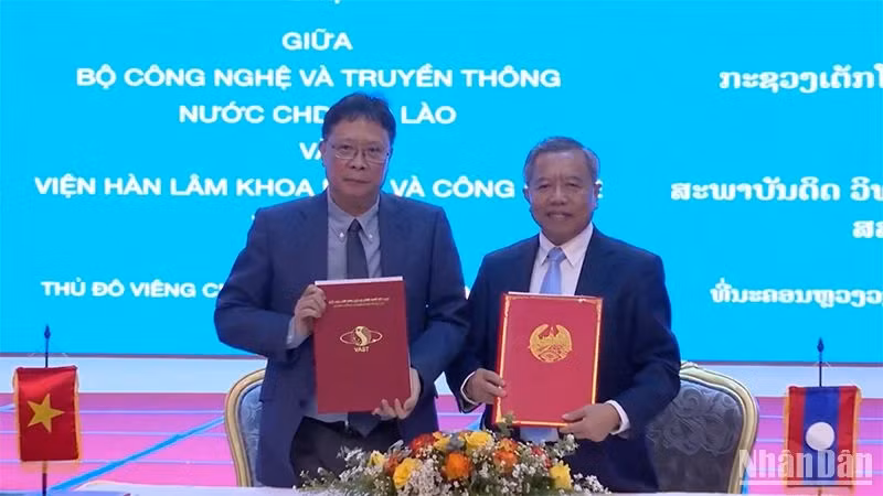 Chau Van Minh, President of the Vietnam Academy of Science and Technology (VAST) (L), and Boviengkham Vongdara, Lao Minister of Technology and Communications, exchange minutes of cooperation. (Photo: NDO/Trinh Dung)