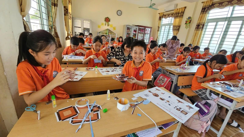 Students of Dai Dong Primary School, Vinh Tuong District are excited with the Hanoi Flagpole model presented by Nhan Dan Newspaper.