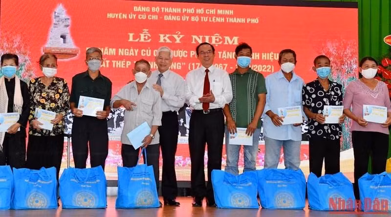 Former President Nguyen Minh Triet and Politburo member cum Secretary of the Ho Chi Minh City Party Committee Nguyen Van Nen present gifts to policy beneficiary families.